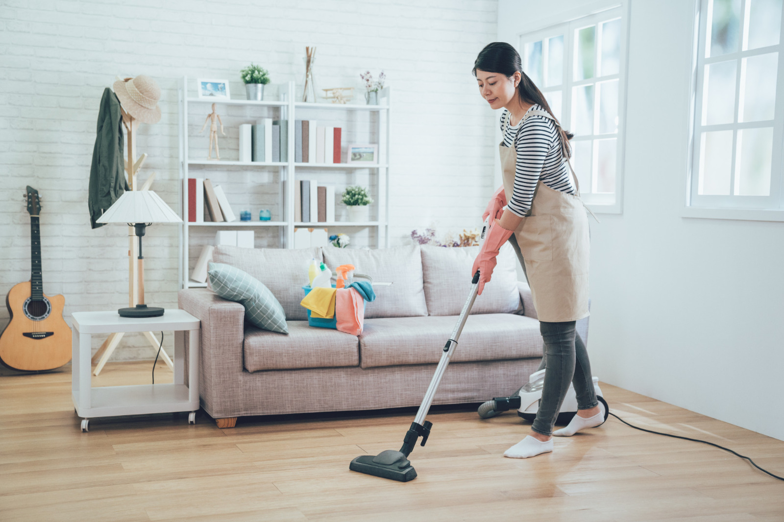 Homeowner vacuuming oak plank Hardwood Floors in an Eltham living room as part of aftercare cleaning.