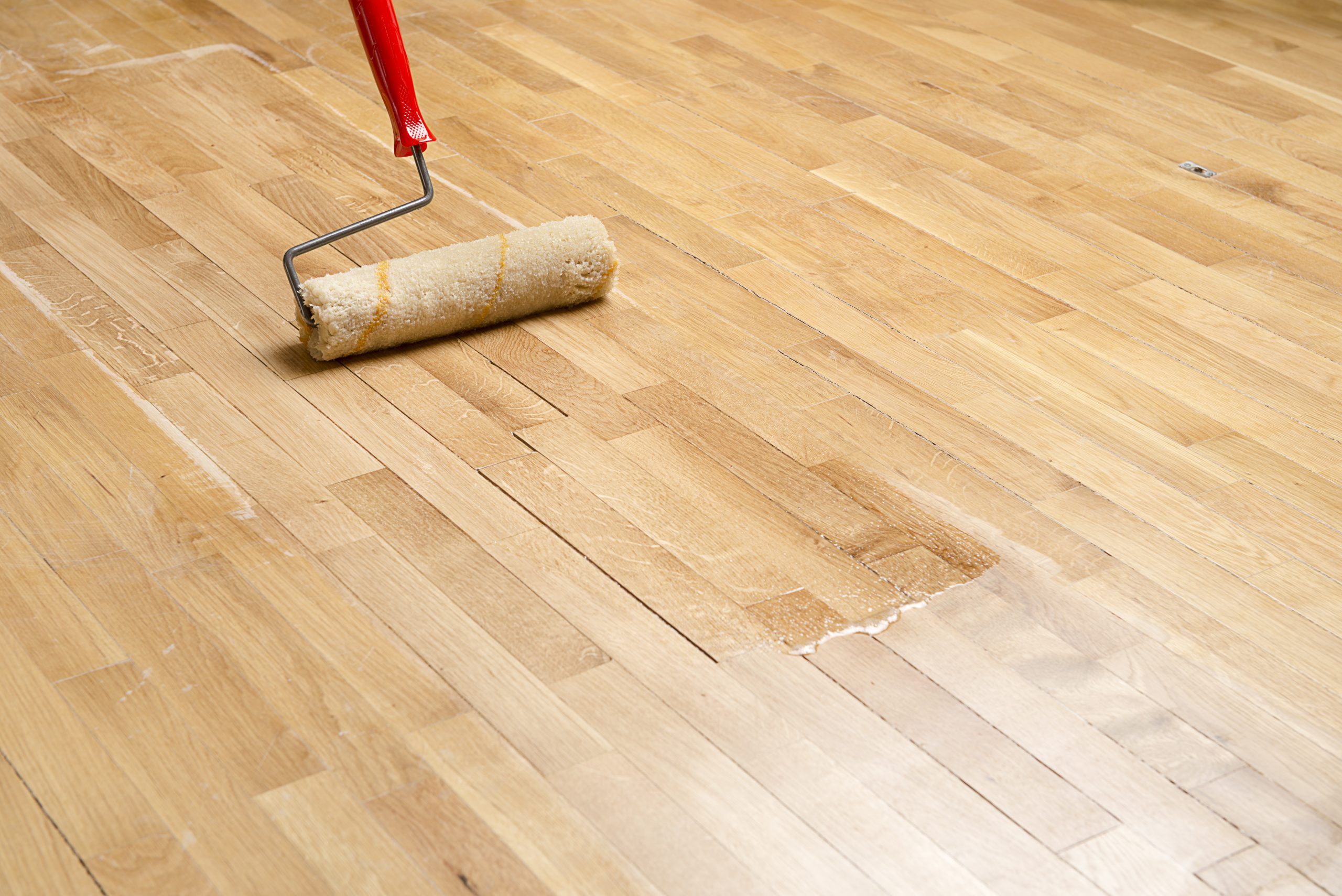 Roller applying a protective coat to freshly sanded oak strip Hardwood Floors in Eltham, creating an even, sealed surface.