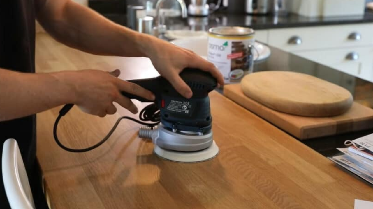 Worktop refinishing in Eltham with a specialist sanding a solid oak hardwood kitchen worktop to create a smooth, hygienic surface.